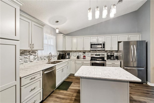 310 Oakley Ln, Destrehan, LA 70047 - kitchen featuring appliances with stainless steel finishes, lofted ceiling, backsplash, dark wood finished floors, and a kitchen island