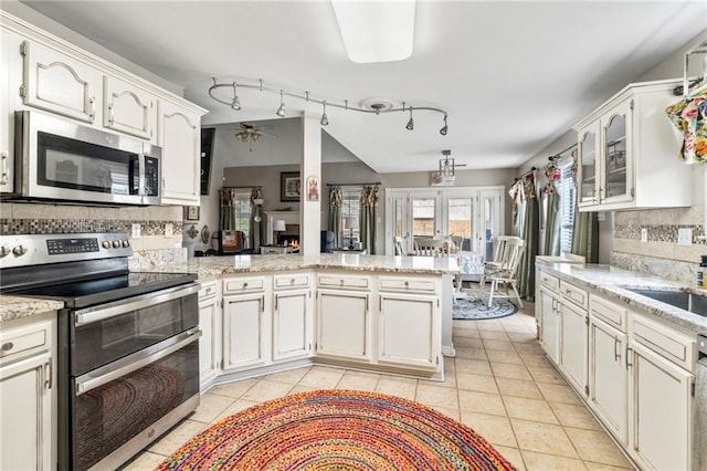 19199 Hector St, Mandeville, LA 70471 - kitchen with stainless steel appliances, a peninsula, backsplash, light tile patterned floors, and white cabinetry