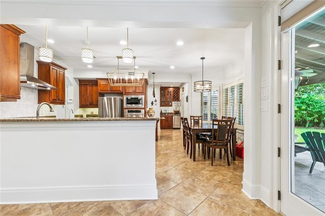 4917 Lake Vista Dr, Metairie, LA 70006 - kitchen with stainless steel appliances, wall chimney exhaust hood, brown cabinets, backsplash, and light stone countertops