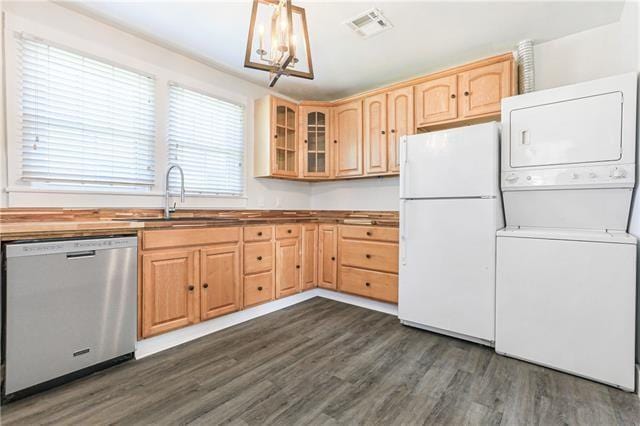 694244 Canal Blvd, New Orleans, LA 70115 - kitchen with stainless steel dishwasher, freestanding refrigerator, stacked washer and clothes dryer, light brown cabinetry, and dark wood-type flooring