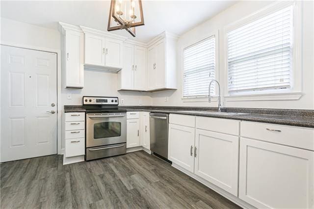 694244 Canal Blvd, New Orleans, LA 70115 - kitchen featuring appliances with stainless steel finishes, a chandelier, dark countertops, white cabinetry, and dark wood-style flooring