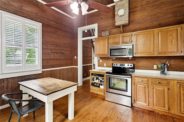 2027 Monroe St, Mandeville, LA 70448 - kitchen with stainless steel appliances, wooden walls, light countertops, a ceiling fan, and light wood finished floors