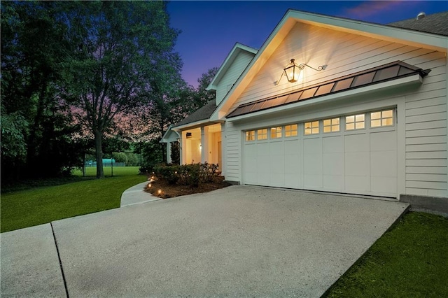 35 Elmwood Loop, Madisonville, LA 70447 - property exterior at dusk featuring a standing seam roof, a lawn, driveway, a metal roof, and a garage