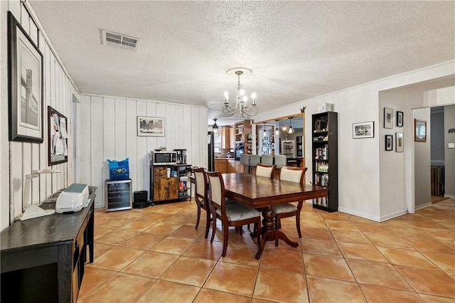 2041 Glencove Ln, Terrytown, LA 70056 - dining space with a chandelier, light tile patterned flooring, wine cooler, a textured ceiling, and crown molding