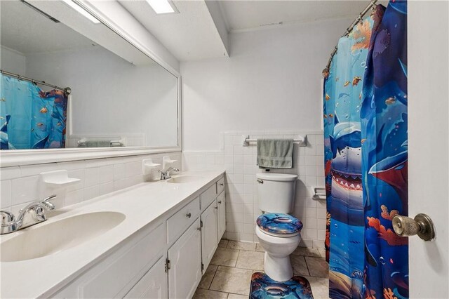 2041 Glencove Ln, Terrytown, LA 70056 - bathroom featuring double vanity, tile patterned floors, tile walls, a wainscoted wall, and a shower with shower curtain