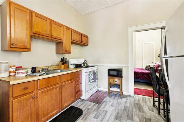 222325 Felicity St, New Orleans, LA 70113 - kitchen featuring white appliances, brown cabinetry, light countertops, and light wood finished floors