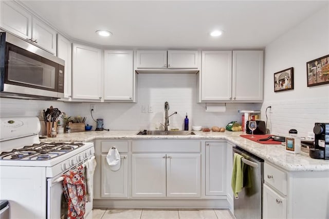 5227-29 Coliseum St, New Orleans, LA 70115 - kitchen with stainless steel appliances, backsplash, light tile patterned floors, white cabinets, and recessed lighting