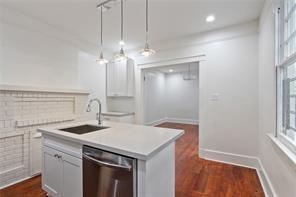 5227-29 Coliseum St, New Orleans, LA 70115 - kitchen featuring stainless steel dishwasher, light countertops, a center island with sink, hanging light fixtures, and dark wood finished floors