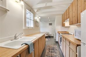 5227-29 Coliseum St, New Orleans, LA 70115 - kitchen with white appliances, brown cabinets, light countertops, and under cabinet range hood