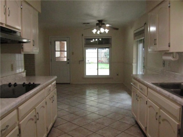 4908 Wills St, Metairie, LA 70006 - kitchen with black electric stovetop, under cabinet range hood, ceiling fan, light countertops, and backsplash