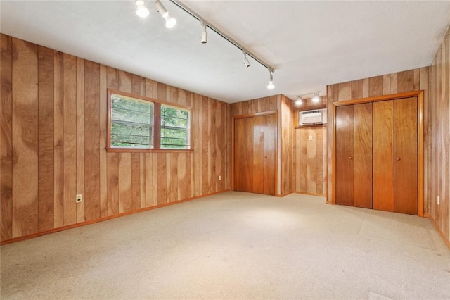 638 Huntlee Dr, New Orleans, LA 70131 - unfurnished bedroom featuring track lighting, a wall mounted air conditioner, wooden walls, carpet, and multiple closets