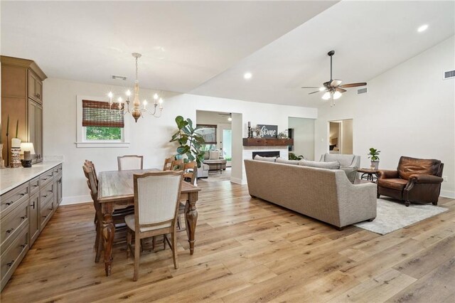 133 Crapemyrtle Rd, Covington, LA 70433 - dining space featuring a chandelier, lofted ceiling, light wood-style flooring, ceiling fan, and a fireplace