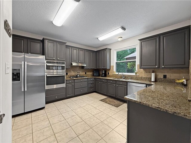 2009 Rubich Ln, Slidell, LA 70461 - kitchen with stainless steel appliances, gray cabinetry, backsplash, a textured ceiling, and dark stone counters