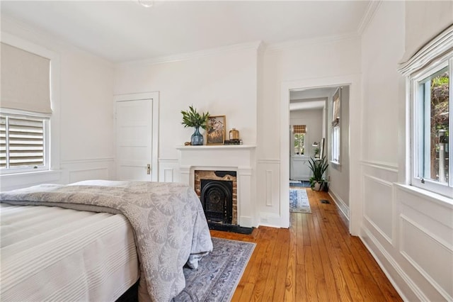 1016 Constantinople St, New Orleans, LA 70115 - bedroom featuring multiple windows, light wood finished floors, a decorative wall, crown molding, and a fireplace