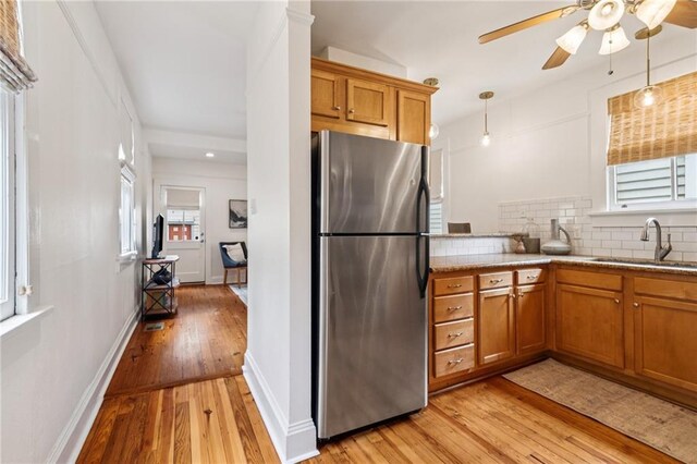 1016 Constantinople St, New Orleans, LA 70115 - kitchen with freestanding refrigerator, brown cabinets, light wood-type flooring, ceiling fan, and decorative backsplash