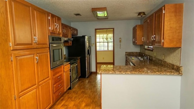 232 Lake Village Blvd, Slidell, LA 70461 - kitchen with appliances with stainless steel finishes, under cabinet range hood, dark wood-type flooring, decorative backsplash, and a textured ceiling