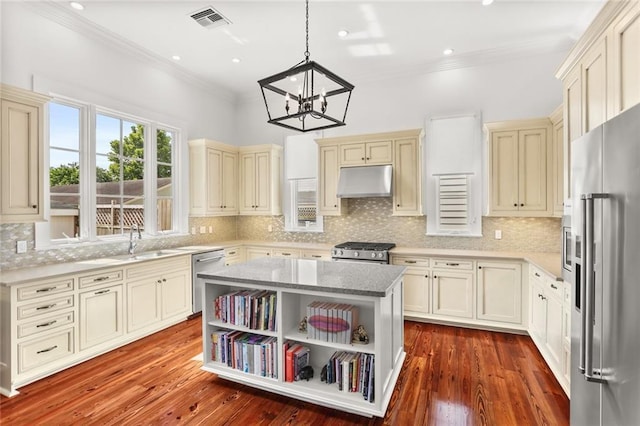 417 Eleonore St, New Orleans, LA 70115 - kitchen featuring cream cabinetry, appliances with stainless steel finishes, under cabinet range hood, a chandelier, and crown molding