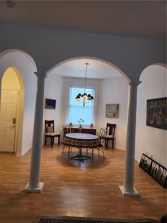 2715 Marengo St, New Orleans, LA 70115 - dining space with light wood-style floors, arched walkways, decorative columns, and a chandelier