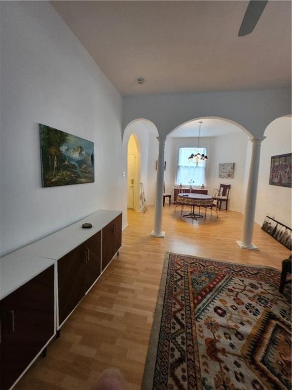 2715 Marengo St, New Orleans, LA 70115 - living room featuring ornate columns, arched walkways, light wood-style flooring, ceiling fan, and a chandelier