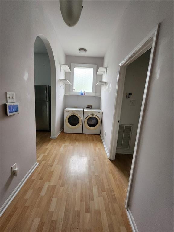 2715 Marengo St, New Orleans, LA 70115 - washroom with washing machine and clothes dryer, light wood-type flooring, and arched walkways