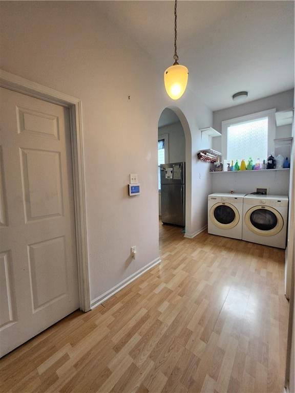 2715 Marengo St, New Orleans, LA 70115 - washroom with washing machine and dryer, light wood-style floors, and arched walkways