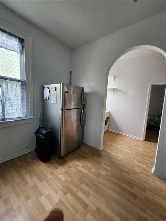 2715 Marengo St, New Orleans, LA 70115 - kitchen with freestanding refrigerator, arched walkways, washer / clothes dryer, and light wood-style flooring