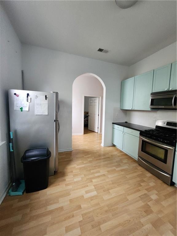 2715 Marengo St, New Orleans, LA 70115 - kitchen with appliances with stainless steel finishes, arched walkways, light wood-type flooring, and dark countertops