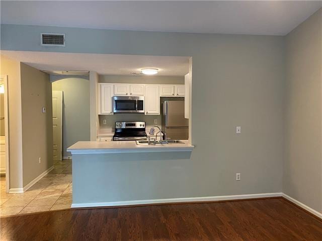 350 Emerald Forest Ave Unit 5202, Covington, LA 70433 - kitchen with appliances with stainless steel finishes, arched walkways, white cabinets, light countertops, and a peninsula