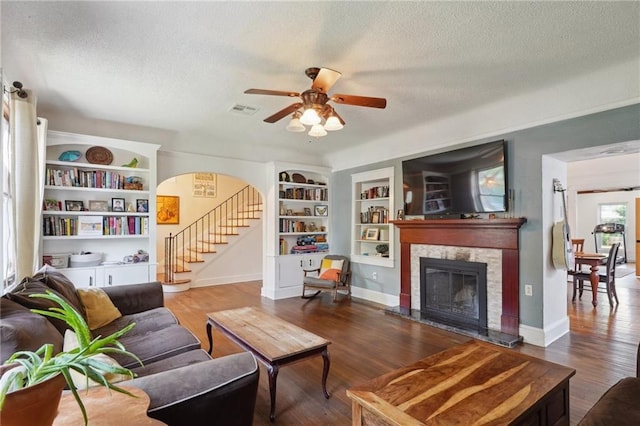 223840 Dante St, New Orleans, LA 70118 - living room featuring a textured ceiling, a ceiling fan, wood finished floors, a glass covered fireplace, and built in features