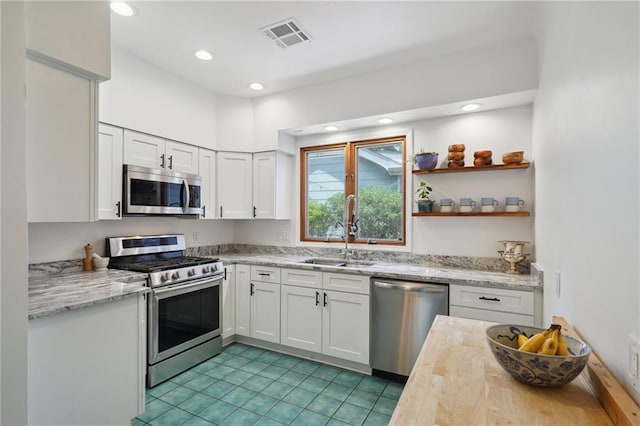 223840 Dante St, New Orleans, LA 70118 - kitchen with appliances with stainless steel finishes, white cabinets, recessed lighting, light stone countertops, and light tile patterned flooring