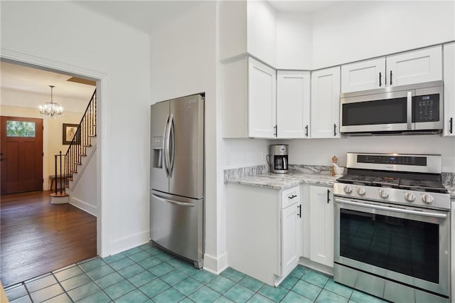 223840 Dante St, New Orleans, LA 70118 - kitchen with appliances with stainless steel finishes, white cabinetry, a chandelier, light stone counters, and light tile patterned flooring