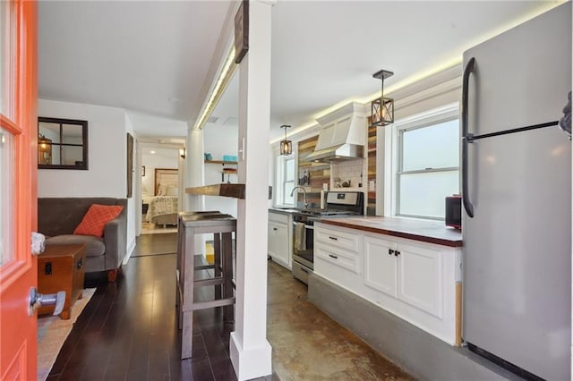 223840 Dante St, New Orleans, LA 70118 - kitchen featuring appliances with stainless steel finishes, premium range hood, hanging light fixtures, white cabinets, and wooden counters