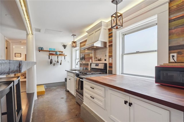 223840 Dante St, New Orleans, LA 70118 - kitchen featuring stainless steel range with gas stovetop, wooden counters, concrete flooring, custom range hood, and decorative light fixtures