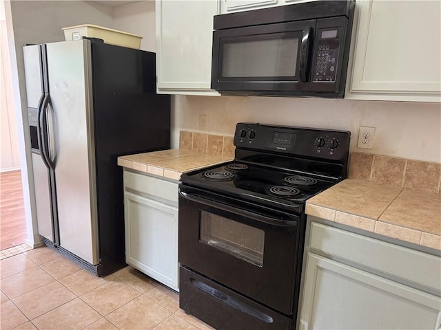 204 Portsmouth Dr, Slidell, LA 70460 - kitchen featuring black appliances, light tile patterned floors, and white cabinets