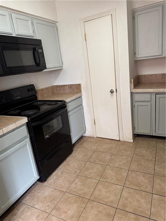 204 Portsmouth Dr, Slidell, LA 70460 - kitchen with black appliances, light countertops, gray cabinetry, and light tile patterned flooring