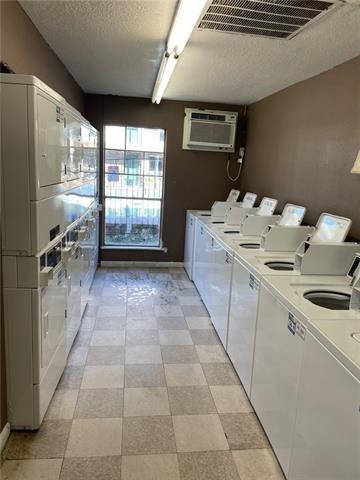 6200 Riverside Dr Unit 625, Metairie, LA 70003 - communal laundry room featuring stacked washer / drying machine, separate washer and dryer, a textured ceiling, a wall unit AC, and light flooring