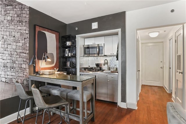 1205 St Charles Ave Unit 704, New Orleans, LA 70130 - kitchen featuring stainless steel microwave, dark wood-style flooring, tasteful backsplash, and white cabinetry