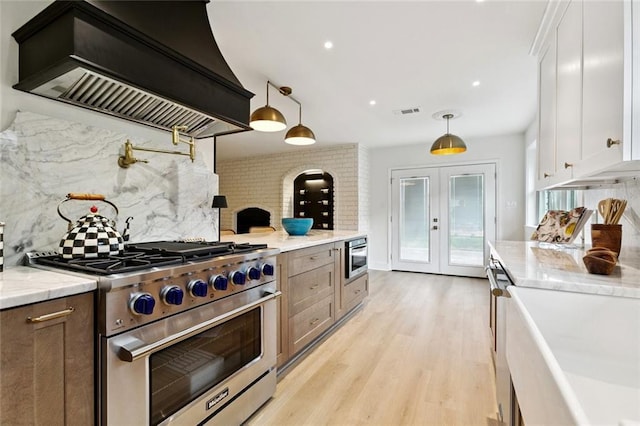 1528 N Cumberland St, Metairie, LA 70003 - kitchen featuring high end range, custom exhaust hood, decorative backsplash, light wood finished floors, and white cabinetry