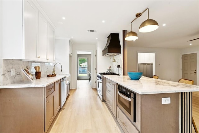 1528 N Cumberland St, Metairie, LA 70003 - kitchen featuring custom range hood, appliances with stainless steel finishes, light wood-style floors, decorative backsplash, and light stone counters