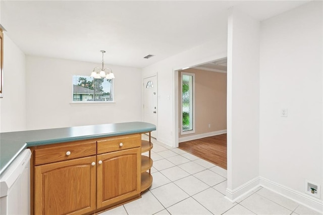 4700 Jasper St, Metairie, LA 70006 - kitchen with light tile patterned flooring, a peninsula, a chandelier, brown cabinetry, and pendant lighting