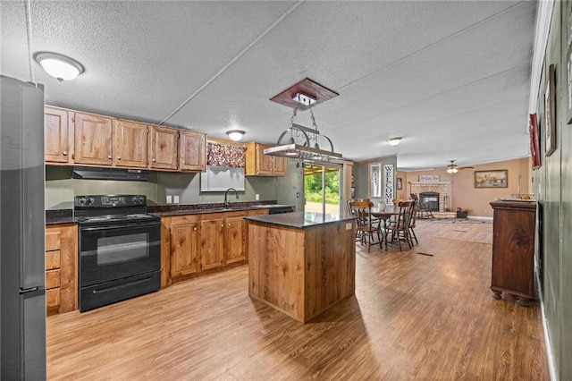 24483 Riley Rd, Pride, LA 70770 - kitchen featuring black electric range oven, under cabinet range hood, freestanding refrigerator, light wood-style flooring, and a kitchen island