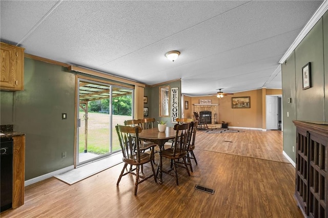 24483 Riley Rd, Pride, LA 70770 - dining space with wood finished floors, a fireplace, a ceiling fan, ornamental molding, and a textured ceiling