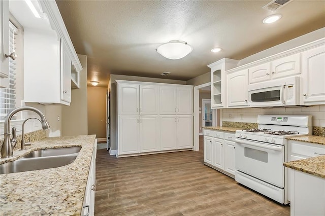 1410 Pecan St, Hammond, LA 70401 - kitchen with white appliances, white cabinetry, decorative backsplash, wood finished floors, and a textured ceiling