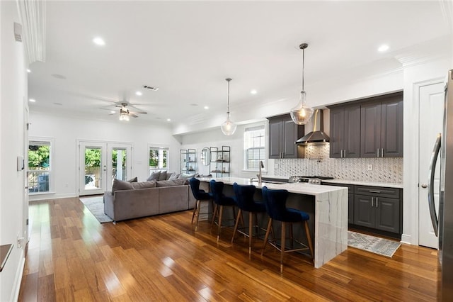 624 Wagner St, New Orleans, LA 70114 - kitchen with wall chimney exhaust hood, hardwood / wood-style floors, decorative backsplash, healthy amount of natural light, and recessed lighting