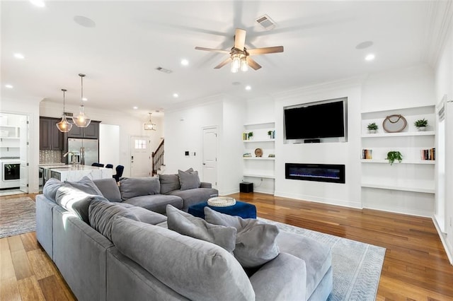 624 Wagner St, New Orleans, LA 70114 - living area featuring crown molding, a ceiling fan, built in shelves, stairs, and light wood finished floors