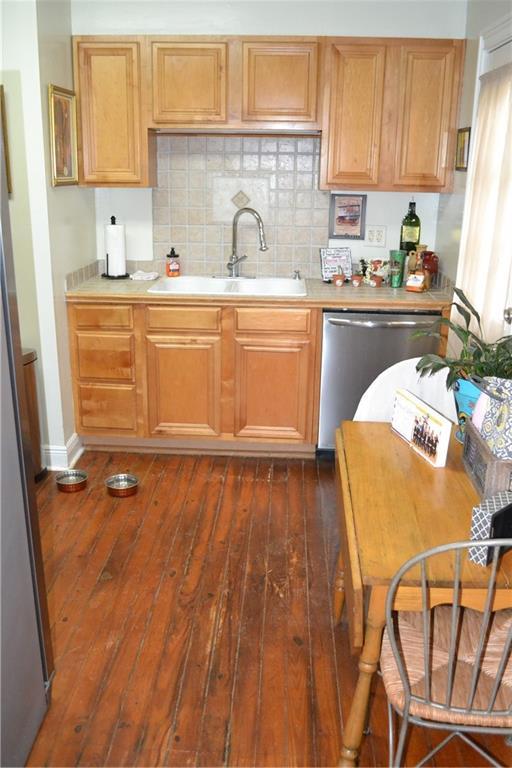 128 Gruner Rd, Metairie, LA 70001 - kitchen featuring stainless steel dishwasher, dark wood-style flooring, tasteful backsplash, and light countertops