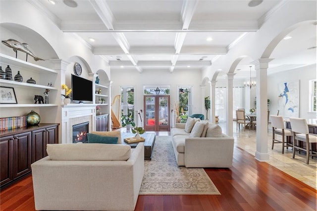 10 Finch St, New Orleans, LA 70124 - living room featuring ornate columns, arched walkways, beamed ceiling, healthy amount of natural light, and a tile fireplace
