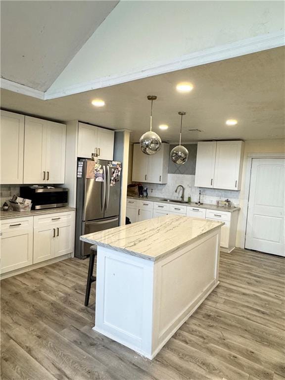 4925 Jasper St, Metairie, LA 70006 - kitchen with appliances with stainless steel finishes, a center island, tasteful backsplash, white cabinets, and lofted ceiling