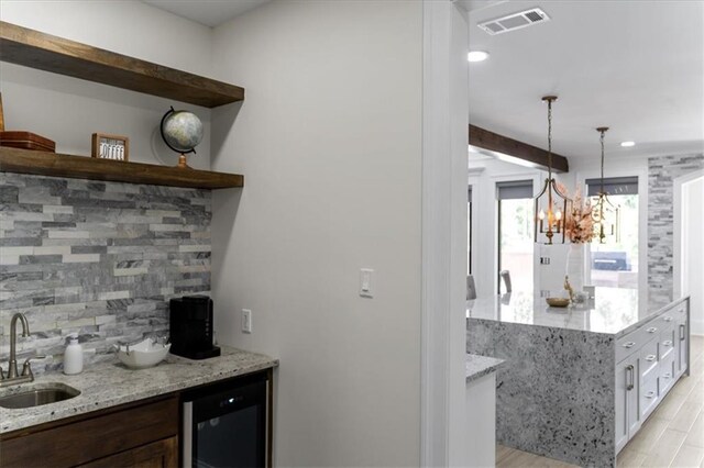 31350 Walker Rd, Walker, LA 70785 - indoor wet bar with wine cooler, tasteful backsplash, light wood-style floors, a chandelier, and hanging light fixtures