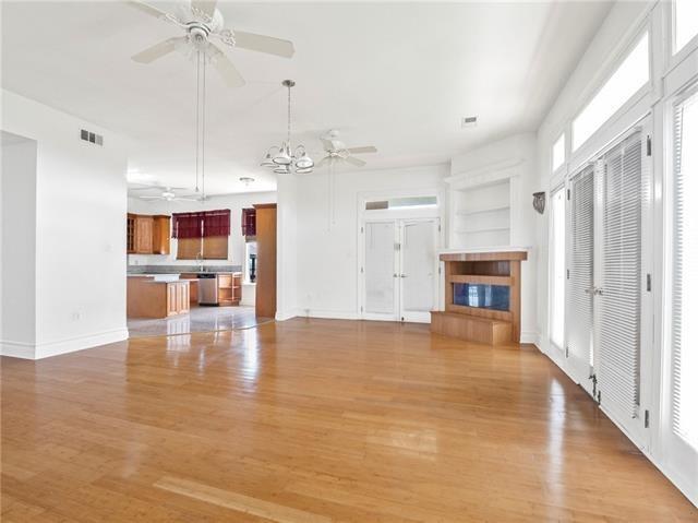30 Clinton Dr, New Orleans, LA 70129 - unfurnished living room with a ceiling fan, light wood-type flooring, a fireplace, and french doors